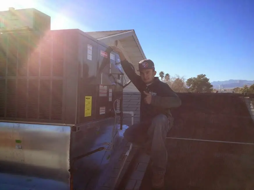 HVAC technician performing Air Duct Repair on a rooftop unit in Asbury